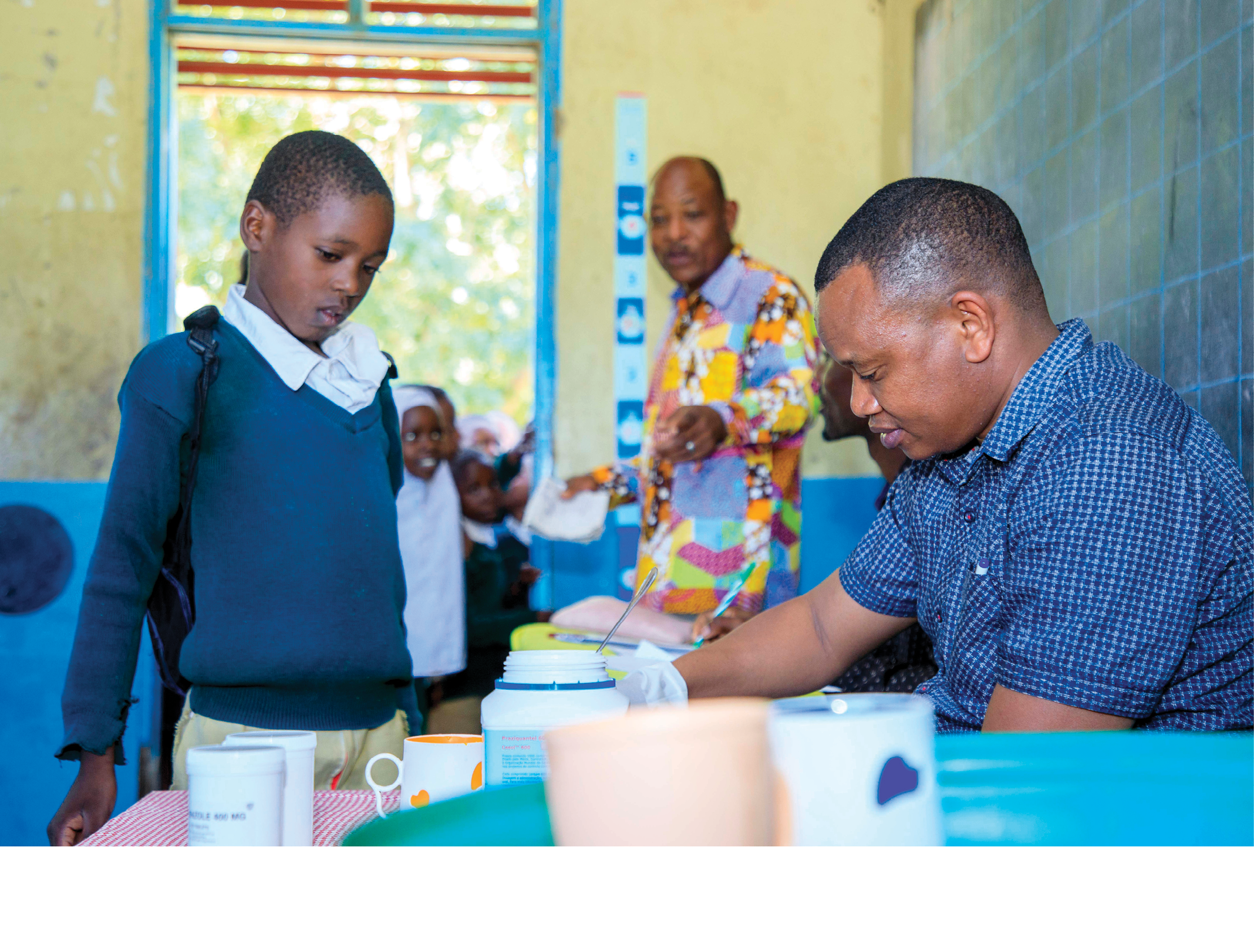 Dr Mohamed Nyati, distributes the drug praziquantel to children during the school mass drug administration campaign. He is the Programme Officer for the Neglected Tropical Diseases Control Programme of  the Ministry of Health in Tanzania.